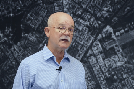 Man wearing glasses and collard shirt standing in front of SAR Data imagery