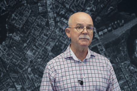 Man wearing glasses and collard shirt standing in front of SAR Data imagery