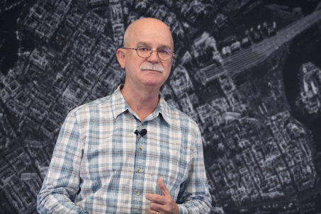 Man wearing glasses and collard shirt standing in front of SAR Data imagery