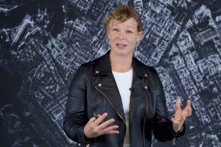 Woman wearing white shirt and black jacked standing in front of SAR Data imagery